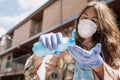 Young woman wearing flu mask and gloves holds a bottle of disinfectant gel to prevent Covid-19 Royalty Free Stock Photo