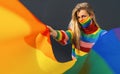 Young woman wearing gay pride face mask during Coronavirus pandemic holding rainbow flag symbol of Lgbtq social movement concept Royalty Free Stock Photo