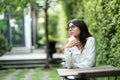 Young woman wearing glasses sitting at green public garden. she