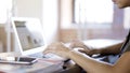 A young woman wearing a green shirt typing at her laptop in an office. Over the shoulder shot Royalty Free Stock Photo