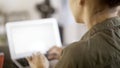 A young woman wearing a green shirt typing at her laptop in an office. Over the shoulder shot Royalty Free Stock Photo