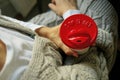 Young woman wearing a grey knitted sweater holding disposable coffee cup with a red cap `I heart it hot`. Royalty Free Stock Photo