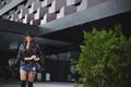 Young woman wearing a hat, leather jacket and denim shorts smiling in urban background. Model girl in casual clothes Royalty Free Stock Photo