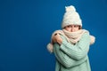 Woman wearing hat and scarf suffering from fever on blue background, space for text. Cold symptoms