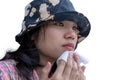 Young woman wearing hat sitting outdoor. Beautiful Asian girl cleaning sweat on her face and using facial tissue on her face Royalty Free Stock Photo