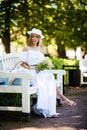 Young woman wearing a hat sitting on a wooden bench and relaxing at the park Royalty Free Stock Photo