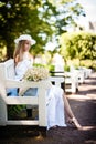 Young woman wearing a hat sitting on a wooden bench and relaxing at the park Royalty Free Stock Photo