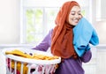 Young woman wearing hijab carrying laundry basket while smelling Royalty Free Stock Photo