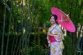 A young woman wearing a Japanese traditional kimono or yukata holding an umbrella is happy and cheerful in the park Royalty Free Stock Photo