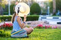 Young woman wearing light blue summer dress and yellow straw hat relaxing on green grass lawn in summer park. Girl in casual Royalty Free Stock Photo