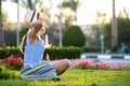 Young woman wearing light blue summer dress and yellow straw hat relaxing on green grass lawn in summer park. Girl in casual Royalty Free Stock Photo