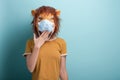 Young woman wearing lion and protection medical mask, covering mouth with hand