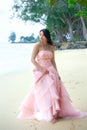Young woman wearing long pink dress on Hawaiian beach
