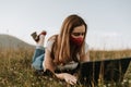 Young women with mask lies in the grass and looking at laptop