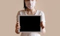 Young woman wearing medical face mask, and holding digital tablet Royalty Free Stock Photo