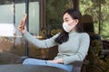 Young woman wearing medical mask making selfie or video call with smartphone at coffee shop Royalty Free Stock Photo