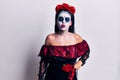 Young woman wearing mexican day of the dead makeup puffing cheeks with funny face