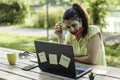 Young woman wearing open protective face mask using laptop outdoors - Pensive female solopreneur working in alternative workspace Royalty Free Stock Photo