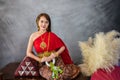 young woman wearing a original traditional red Thai dress and golden ornaments sit holding a jasmine garland. Thai national Royalty Free Stock Photo