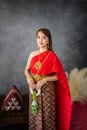 young woman wearing a original traditional red Thai dress and golden ornaments stands holding a jasmine garland. Thai national Royalty Free Stock Photo