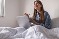 Woman using laptop computer and having breakfast in bed Royalty Free Stock Photo