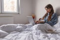 Woman working using laptop computer and having breakfast in bed Royalty Free Stock Photo