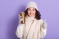 Young woman wearing pale pink scarf, cap, gloves and warm white sweater drinking hot tea or coffee from thermo mug, developing Royalty Free Stock Photo