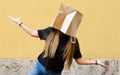 Girl wearing a paper bag over her head in front of yellow background Royalty Free Stock Photo