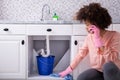 Woman Calling Plumber In Front Of Leaking From Sink Pipe Royalty Free Stock Photo