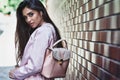 Young woman in pink jacket carrying backpack walking near wall l Royalty Free Stock Photo