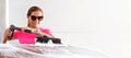 Young woman wearing pink t shirt and sunglasses cleaning her car in self serve carwash, wide banner with space for text right side Royalty Free Stock Photo