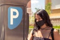 Young woman wearing protective mask using parking machine on the street Royalty Free Stock Photo