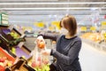 Young woman wearing protective medical face mask shopping in supermarket during coronavirus pneumonia outbreak Royalty Free Stock Photo