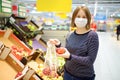 Young woman wearing protective medical face mask shopping in supermarket during coronavirus pneumonia outbreak Royalty Free Stock Photo