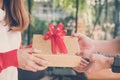 woman wearing red cardigan give gift box to a man. hand get pres Royalty Free Stock Photo