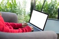 woman wearing red sweater typing on computer at home. female adult sitting on armchair using laptop at cafe. education, working c Royalty Free Stock Photo