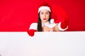 Young woman wearing santa claus costume holding blank empty banner with open hand doing stop sign with serious and confident Royalty Free Stock Photo