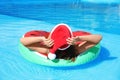 Young woman wearing Santa Claus hat on inflatable ring in swimming pool. Christmas vacation Royalty Free Stock Photo