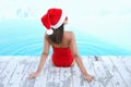 Young woman wearing Santa Claus hat near swimming pool, back view. Christmas vacation Royalty Free Stock Photo