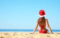 Woman wearing Santa hat and bikini on beach, space for text. Christmas vacation Royalty Free Stock Photo