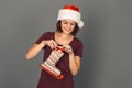 Christmas Time. Young woman in santa hat isolated on grey putting present into skate boot smiling excited Royalty Free Stock Photo