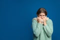 Woman wearing scarf suffering from fever on blue background, space for text. Cold symptoms