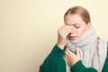 Woman wearing scarf suffering from headache on light background, space for text. Cold symptoms