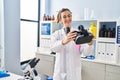 Young woman wearing scientist uniform holding virtual reality goggles at laboratory Royalty Free Stock Photo