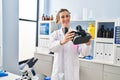 Young woman wearing scientist uniform holding virtual reality goggles at laboratory Royalty Free Stock Photo