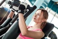 Young girl in sport gloves in gym healthy lifestyle sitting on machine holding handles thoughtful close-up