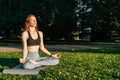 Young woman wearing sportswear is meditating sitting in lotus position on yoga mat with closed eyes Royalty Free Stock Photo