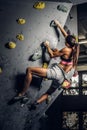 Young woman wearing sportswear practicing rock-climbing on a wall indoors Royalty Free Stock Photo