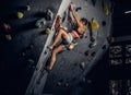 Young woman wearing sportswear practicing rock-climbing on a wall indoors Royalty Free Stock Photo