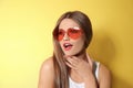 Young woman wearing stylish heart shaped sunglasses on background